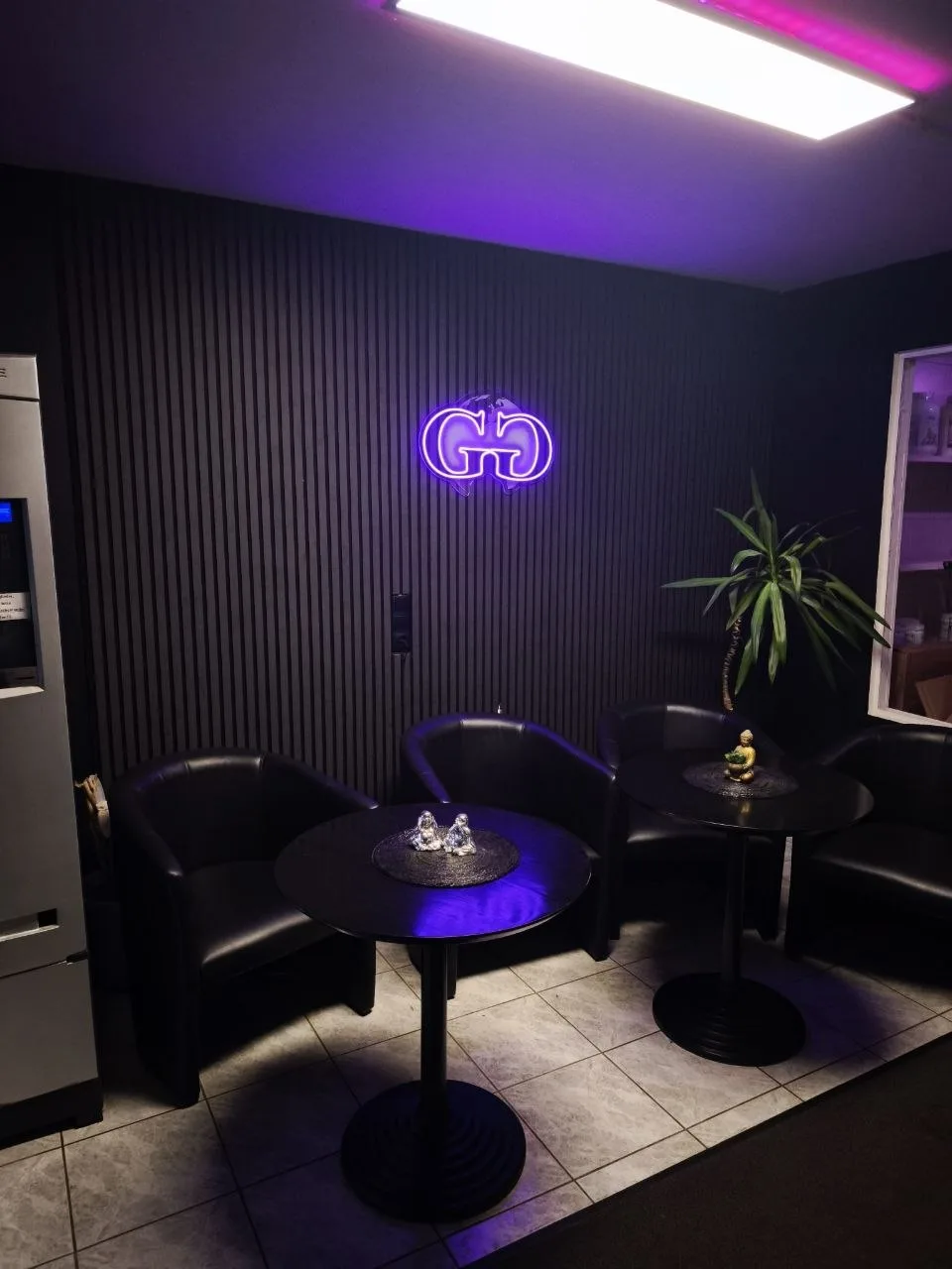 Lounge-Ecke mit Sitzgruppe und Global-Gym-Leuchtschrift